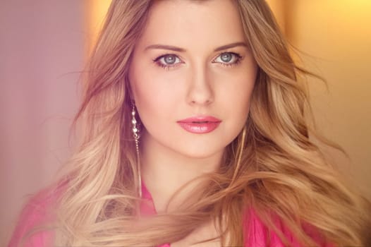Woman with blue eyes and long, voluminous blonde hair styled in soft curls, wearing pink dress and elegant earrings, dreamy and feminine look idea
