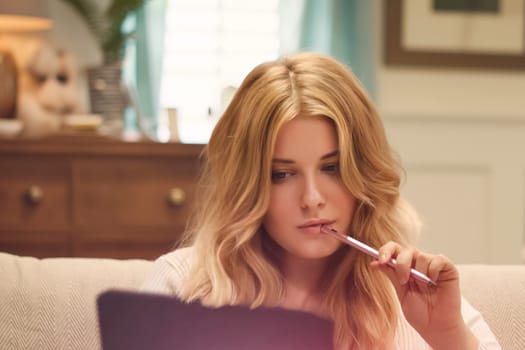 Woman, pen and laptop, thoughtful planning and creative brainstorming. Blonde beautiful woman, remote work and online productivity on sofa, casual elegance and focus on project goals idea