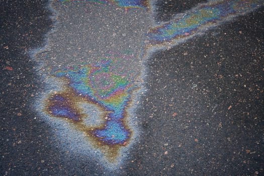 A patch of oil on a soaked roadway symbolizing the threat of pollution to nature