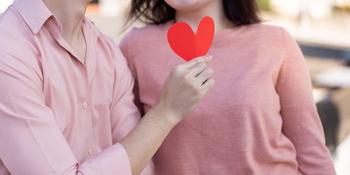 A couple shares a tender moment holding a heart symbol to celebrate their love during Valentine's Day.