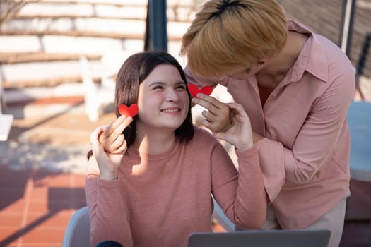 A couple shares joyful moments in a cozy outdoor setting exchanging heart-shaped tokens of love on a warm Valentine's Day outing.