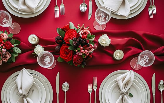 Festive table setting with candles and arrangement of beautiful red flowers. Holiday concept. High quality photo