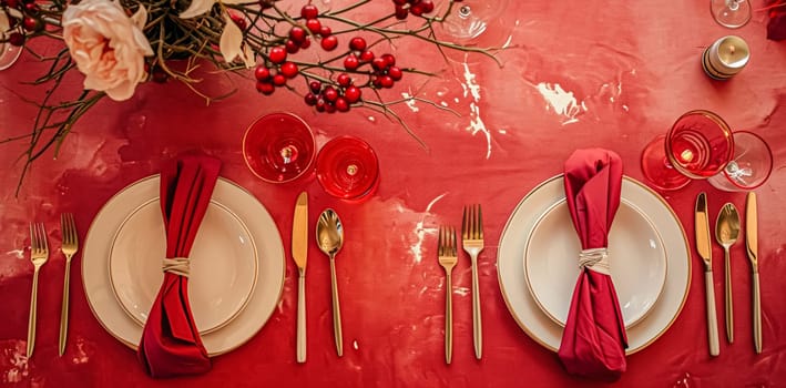 Festive table setting with candles and arrangement of beautiful red flowers. Holiday concept. High quality photo