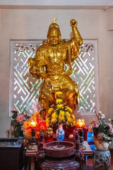 Golden statue of a warrior inside a temple on a Buddhist pagoda in Vietnam in Asia