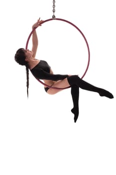 Side view of beautiful charming gymnast sitting on hung hula hoop on white background