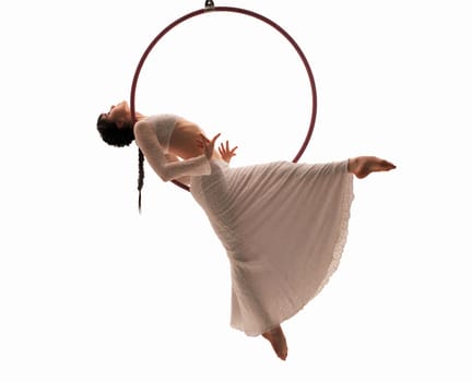 Side view of sensual young woman in white apparel hanging on ring and dancing against white background