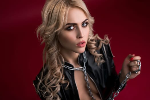 Sexy blonde with locks and chain on her neck wearing black leather jacket portrait