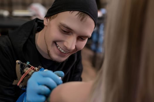 Happy master doing tattoo on the girl s shoulder shot in salon