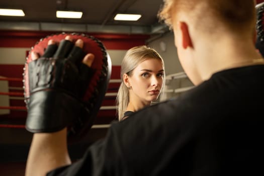 Pretty girl and man in boxing gloves in boxing ring close up view