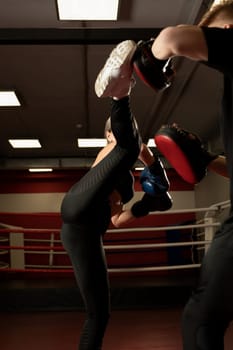 Woman in boxing gloves fighting with a man in a sports gym