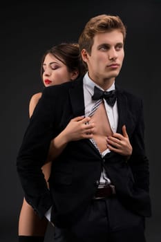 Handsome man in a suit and bowtie and his girlfirend topless in shot