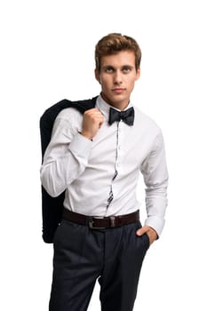 Elegant young man in white shirt standing holding coat over shoulder and looking at camera on white background