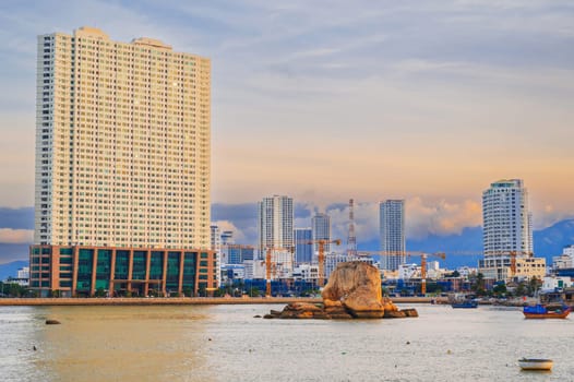 View of the Kai River with fishing boats against the backdrop of poor neighborhoods and modern high-rise expensive real estate in the Asian city of Nha Trang, Vietnam