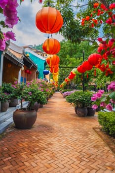 Red paper lanterns hung in the courtyard of a house on a sunny day among the lush greenery in an eastern country. traditional Chinese New Year decoration