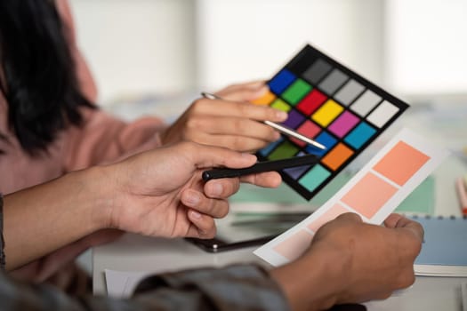 A design team enthusiastically selects color palettes showcasing teamwork and creativity in a modern office environment.
