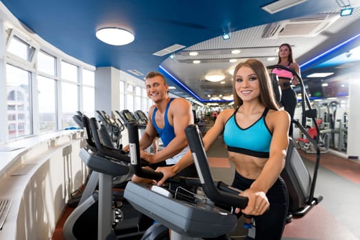 Young sporty couple exercising on simulators in a gym