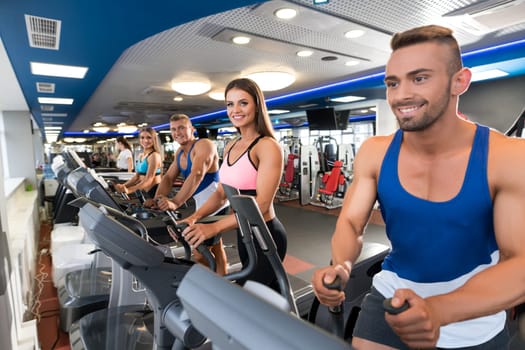 Young sporty people exercising on simulators in a gym