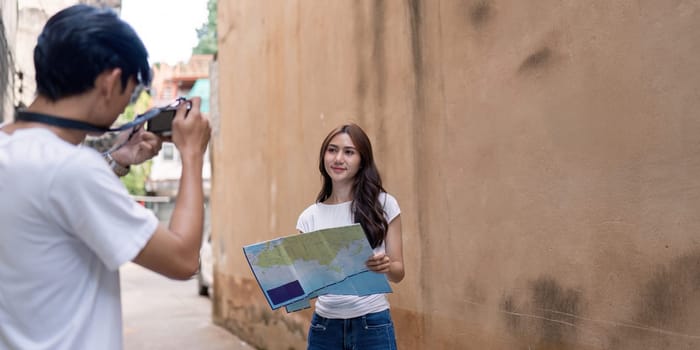 A couple adventures through a vibrant city capturing memories and navigating with a map.