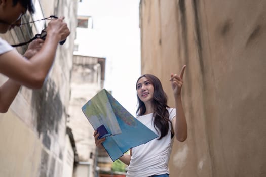 A couple enjoys their travel adventure an urban alley while capturing memorable moments on camera.
