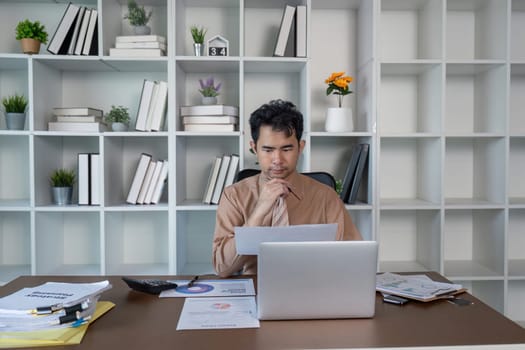 A focused individual reviews important business documents in a modern home office setting.