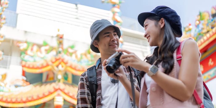 A joyful couple captures memories while a vibrant cultural landmark showcasing their love for travel and adventure.