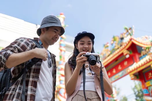 A couple joyfully captures their travel memories at a vibrant cultural festival.