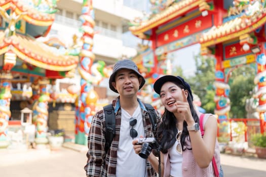 A couple joyfully explores a colorful cultural site capturing memories with their camera amidst vibrant surroundings.