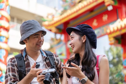 A couple enjoys capturing memories during their travel adventure in a lively city filled with cultural landmarks.