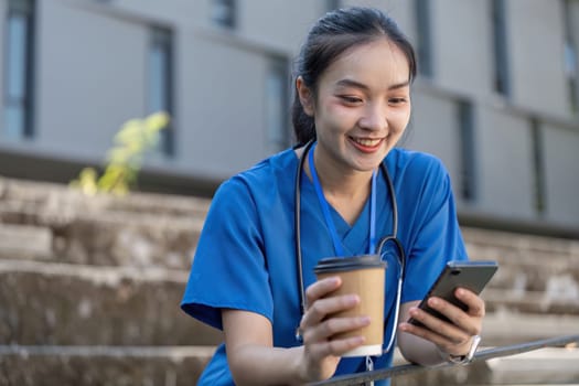 A nurse blends work and relaxation sipping coffee and checking her phone in a lively urban park showcasing a balanced lifestyle.