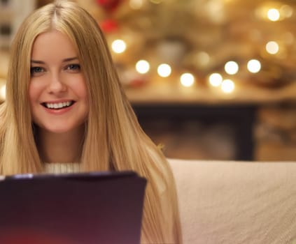 Woman, laptop, and Christmas, online shopping and holiday planning. Blonde beautiful woman, festive mood and electronic transaction, on sofa, ecommerce and gift shopping idea