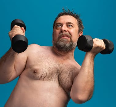 A fit elderly man is engaged in a strength training exercise indoors, lifting dumbbells with determination. He is focused on maintaining his physical health and fitness.