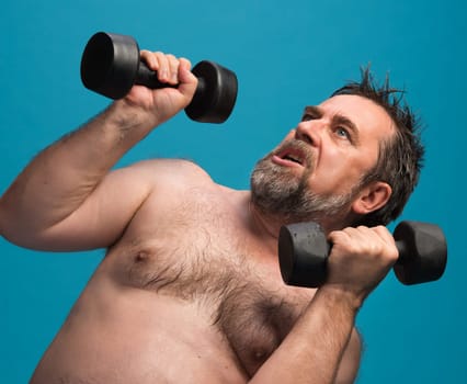 An elderly man is engaged in an intense workout, lifting dumbbells with determination. He is shirtless and focused, showcasing strength and dedication to fitness.