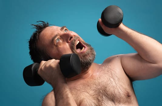 An elderly man lifts dumbbells in an effort-filled workout. He shows determination and focus while exercising. The bright background highlights his commitment to fitness and health.