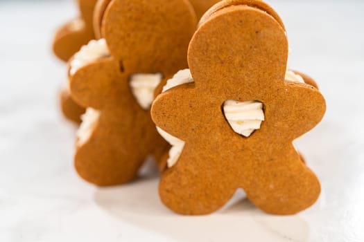 Gingerbread cookies filled with eggnog buttercream stand out, their rich hue complementing the eggnog buttercream, against a gentle background. These festive treats exude a homemade allure.