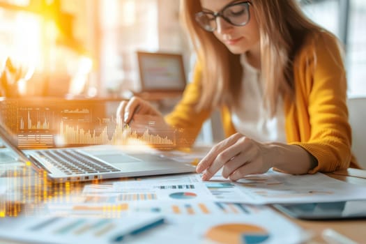 A businesswoman analyzes financial reports on a laptop in a modern office, focusing on charts and graphs. Her workspace showcases productivity and strategy.
