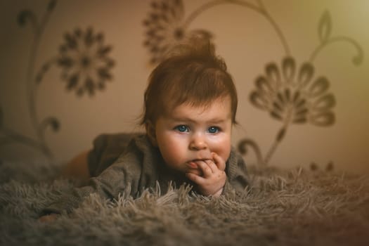 Cute baby girl in brown clothes close up crawling on bed. Adorable kid portrait. 5 month old child. High quality photo
