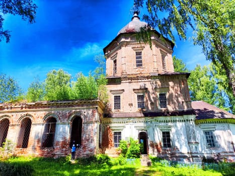 A derelict church surrounded by lush vegetation and trees, showcasing rich architectural details.