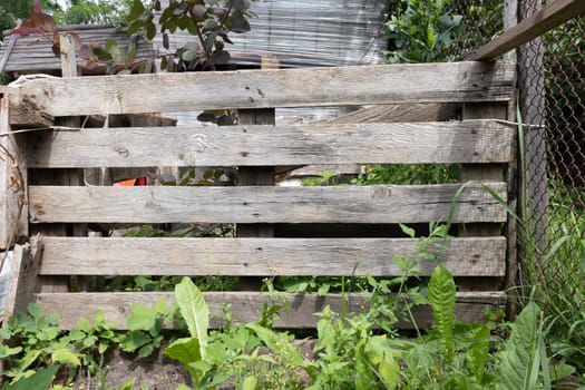 A rustic wooden fence with weathered planks and natural grain patterns, surrounded by greenery in an outdoor environment.