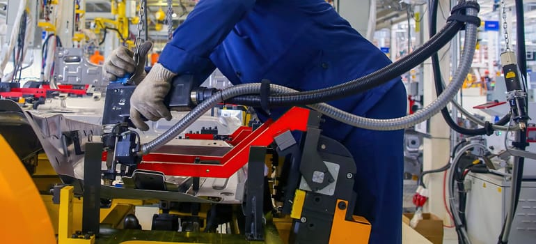 Dedicated professional operates advanced machinery, ensuring quality assembly in a vibrant industrial environment during daylight hours.