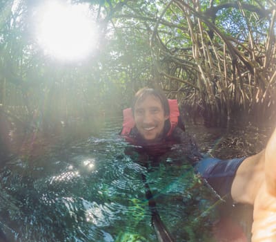 09.12.24, Playa Del Carmen, Mexico: Man tourist standing in the water of a cenote at Xcaret park wearing a marked life jacket. Mexican tourism in natural parks. Adventure, relaxation, and eco-tourism concept in Quintana Roo.