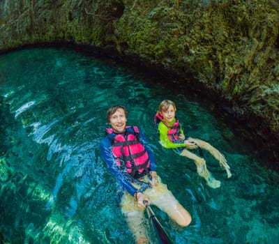 09.12.24, Playa Del Carmen, Mexico: Father and son tourists in the water of a cenote at Xcaret park wearing marked life jackets. Mexican tourism in natural parks. Family bonding, eco-tourism, and adventure concept in Quintana Roo.