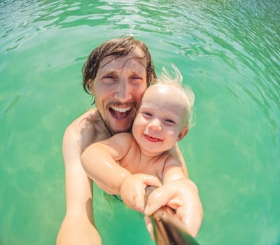 Toddler and father joyfully swimming in the turquoise Caribbean Sea. Family bonding, seaside fun, and tropical vacation concept.