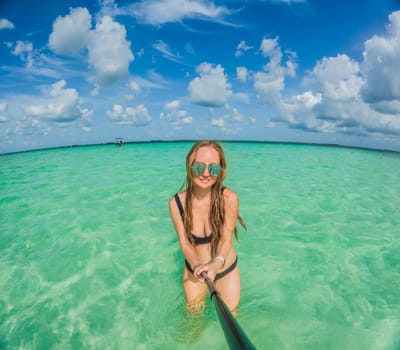 Woman standing in the crystal-clear waters of Lake Bacalar, Mexico, enjoying the serene beauty of the landscape. Tranquil moment in nature, outdoor escape, and relaxation concept.