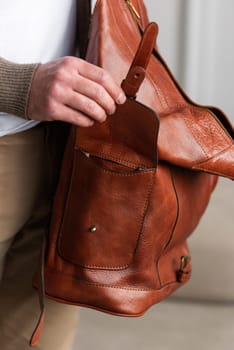 A fashionable man stands with a yellow brown backpack in a contemporary room, embodying urban style and professionalism.
