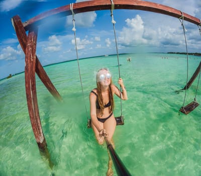 Woman standing in the crystal-clear waters of Lake Bacalar, Mexico, enjoying the serene beauty of the landscape. Tranquil moment in nature, outdoor escape, and relaxation concept.