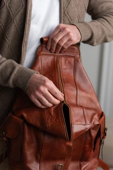 A fashionable man stands with a yellow brown backpack in a contemporary room, embodying urban style and professionalism.
