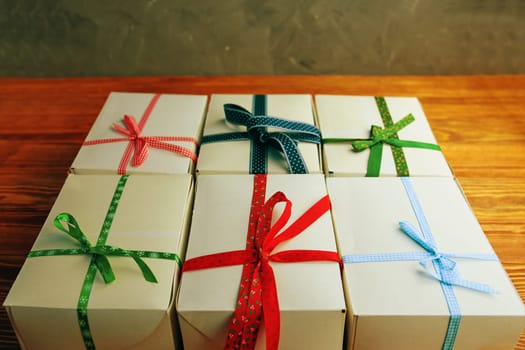 Stack of gift wrapped Christmas presents. A stack of gifts of white colors tied with different ribbons on a wooden table. Flat lay.