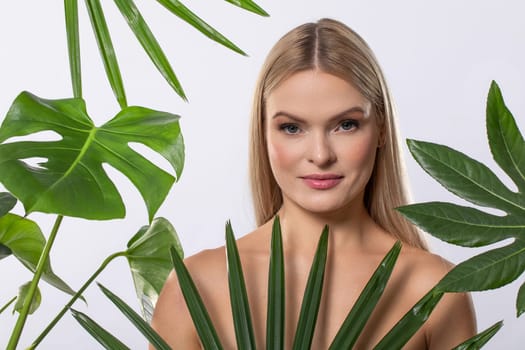 A beautifully serene portrait of a model elegantly surrounded by lush tropical leaves, showcasing her natural beauty