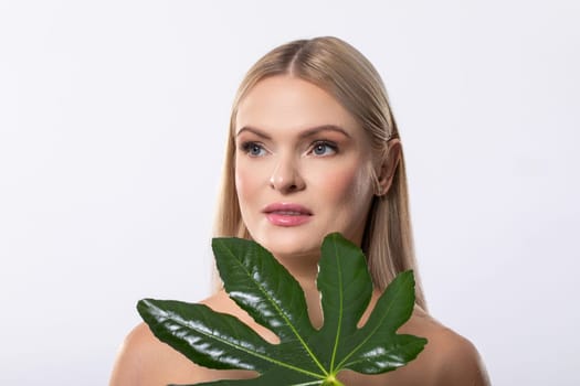 A captivating portrait of a beautiful woman gracefully holding a vibrant green leaf, radiating natural beauty