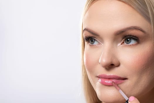 A woman enhances her beauty by skillfully applying lip gloss, showcasing her perfect makeup routine